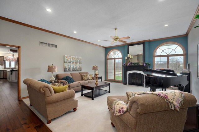 304 Reavley Dr, Lamar, MO 64759 - living area featuring visible vents, crown molding, a fireplace, a textured ceiling, and a ceiling fan