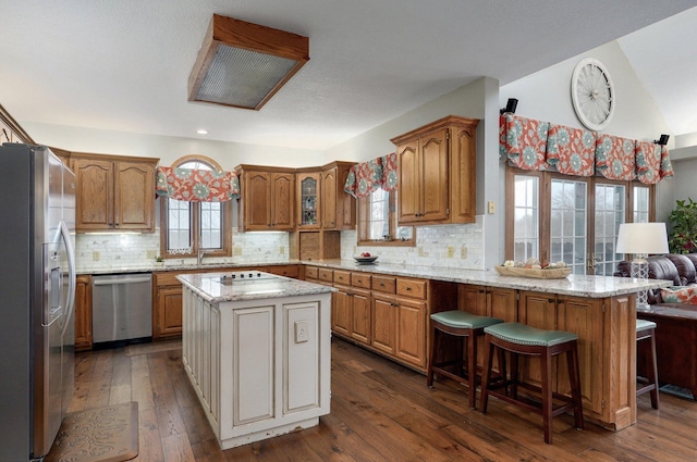 304 Reavley Dr, Lamar, MO 64759 - kitchen with stainless steel appliances, decorative backsplash, dark wood-style flooring, and brown cabinetry