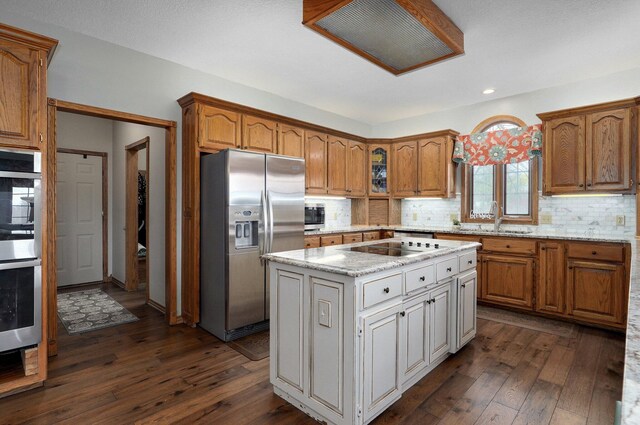 304 Reavley Dr, Lamar, MO 64759 - kitchen with dark wood-type flooring, a sink, a center island, stainless steel appliances, and decorative backsplash