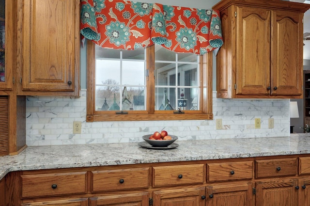 304 Reavley Dr, Lamar, MO 64759 - kitchen featuring brown cabinetry, decorative backsplash, and light stone counters