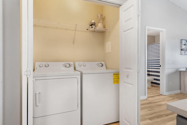 laundry room featuring washer and clothes dryer, laundry area, light wood-style flooring, and baseboards