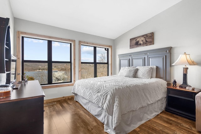 bedroom with vaulted ceiling, visible vents, dark wood-type flooring, and baseboards