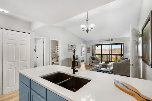 kitchen with decorative light fixtures, open floor plan, an inviting chandelier, blue cabinets, and a sink