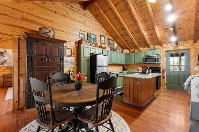 dining space with light wood-style floors, beam ceiling, wooden walls, and wooden ceiling