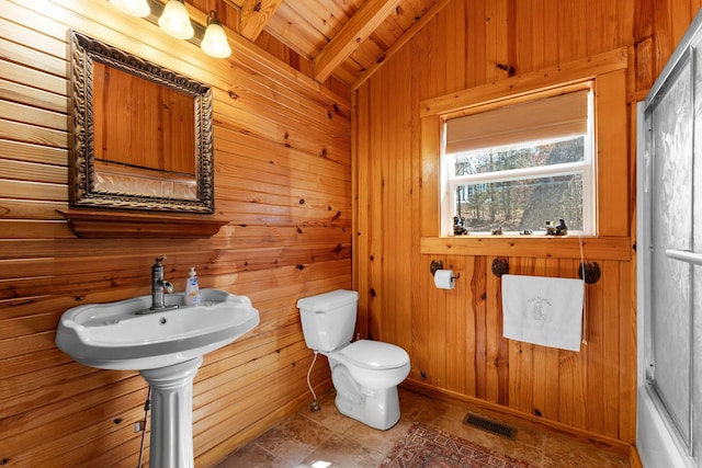 bathroom with visible vents, beam ceiling, wood ceiling, wood walls, and toilet
