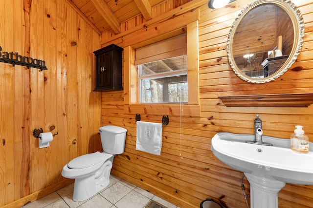 bathroom featuring tile patterned flooring, wooden walls, and toilet