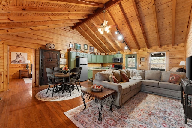 living area with beamed ceiling, high vaulted ceiling, wood finished floors, wooden walls, and wooden ceiling