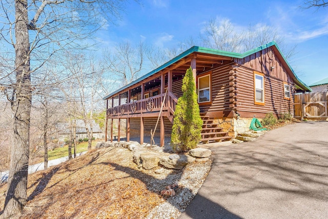 view of front of house with log siding, board and batten siding, stairs, and driveway
