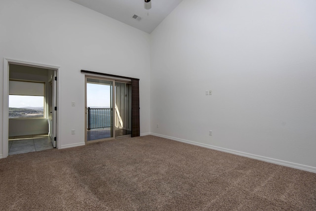 carpeted empty room featuring baseboards, visible vents, high vaulted ceiling, and a ceiling fan
