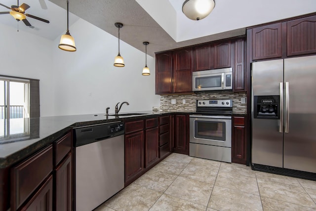 kitchen with backsplash, decorative light fixtures, dark stone countertops, stainless steel appliances, and a sink