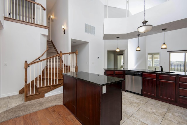 kitchen with visible vents, a sink, stainless steel dishwasher, reddish brown cabinets, and a center island