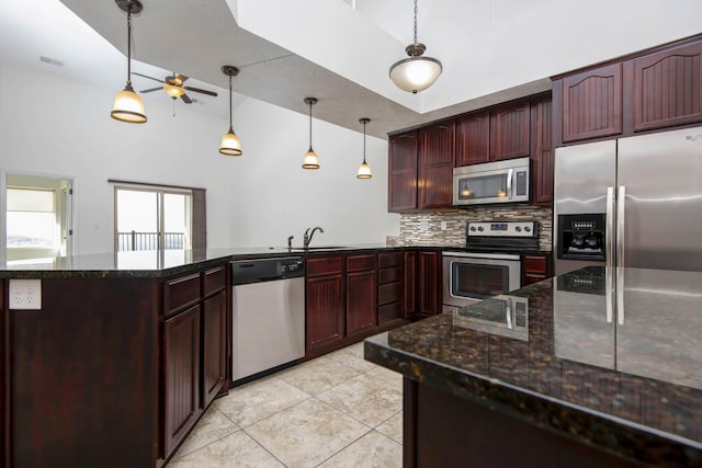kitchen featuring a ceiling fan, a sink, stainless steel appliances, a peninsula, and decorative backsplash