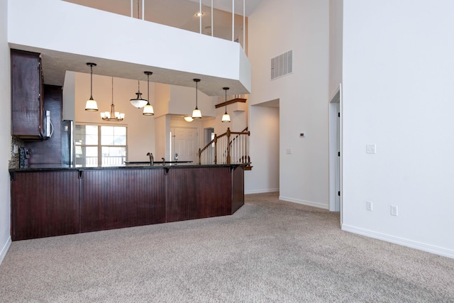 kitchen with visible vents, dark countertops, carpet floors, a breakfast bar area, and a chandelier