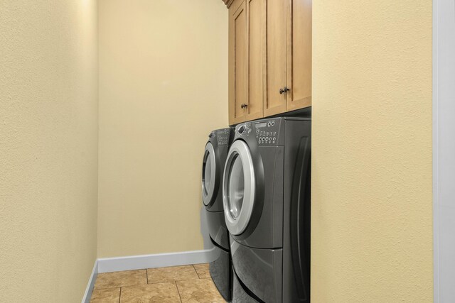 washroom with cabinet space, light tile patterned floors, independent washer and dryer, and baseboards