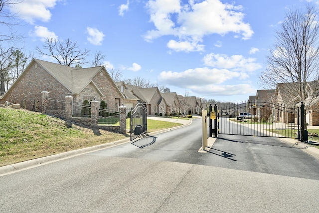 view of road with a gated entry, a residential view, curbs, and a gate