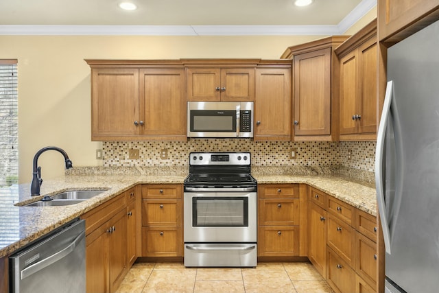 kitchen featuring ornamental molding, decorative backsplash, brown cabinets, appliances with stainless steel finishes, and a sink