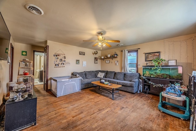 living area featuring visible vents, a ceiling fan, and wood finished floors