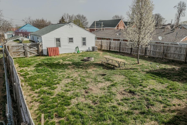 view of yard with cooling unit, an outdoor fire pit, a fenced backyard, and a gate
