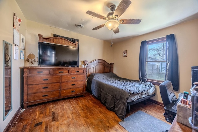 bedroom with ceiling fan, visible vents, baseboards, and dark wood-style floors