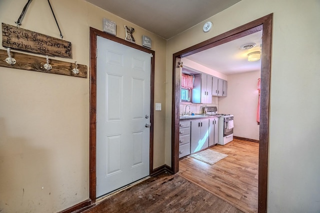 doorway with a sink, baseboards, visible vents, and light wood-type flooring