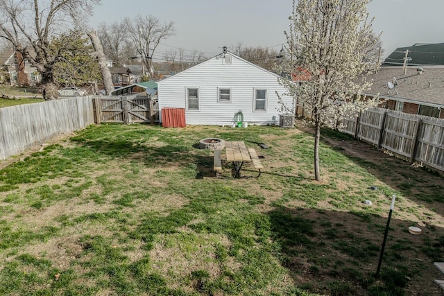 view of yard with cooling unit, a fire pit, a fenced backyard, and a gate