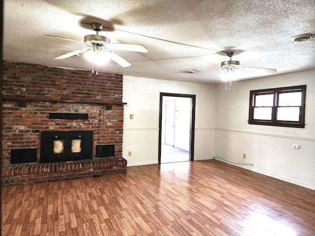 1622 W Fairview Ave, Carthage, MO 64836 - unfurnished living room featuring a ceiling fan, wood finished floors, baseboards, a fireplace, and a textured ceiling