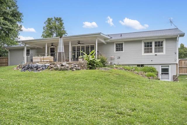rear view of property featuring ceiling fan, fence, metal roof, and a lawn
