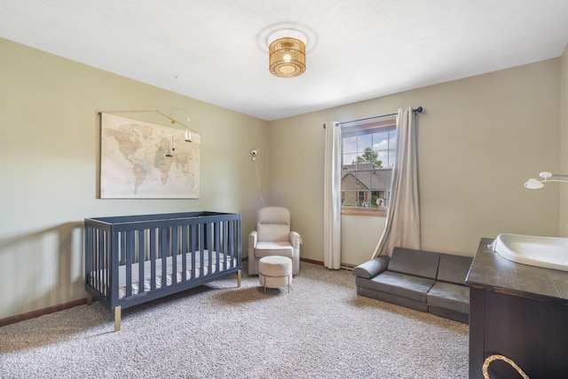carpeted bedroom featuring baseboards and a crib