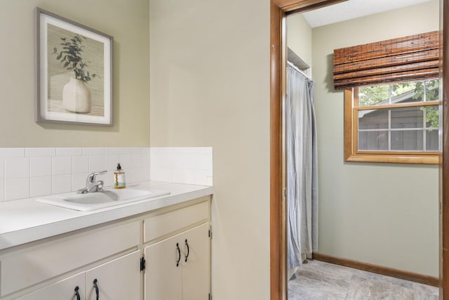 full bathroom with vanity, baseboards, and backsplash