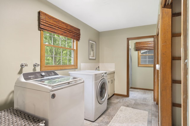 clothes washing area featuring baseboards, cabinet space, and washing machine and dryer