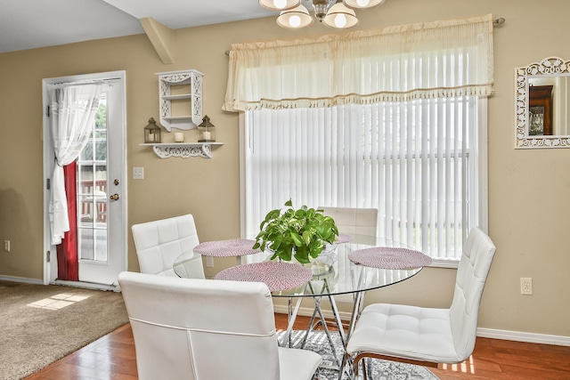 dining area featuring wood finished floors, an inviting chandelier, and baseboards