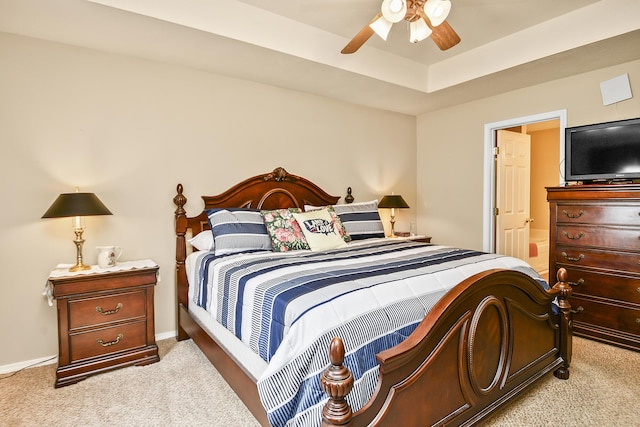bedroom with a tray ceiling, ceiling fan, light colored carpet, and baseboards