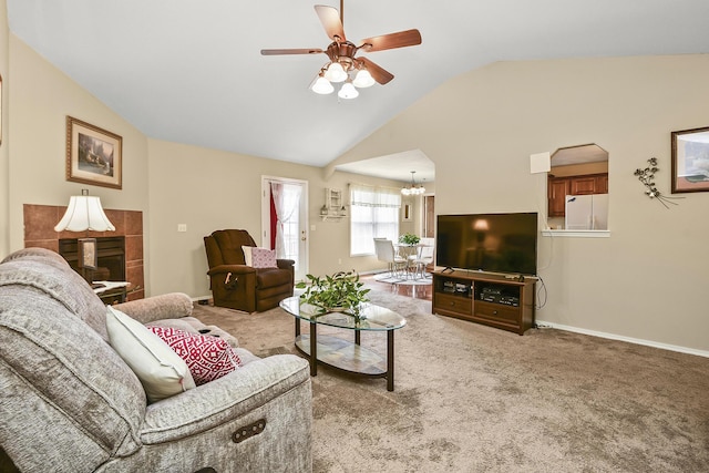 carpeted living room featuring a tiled fireplace, ceiling fan with notable chandelier, baseboards, and lofted ceiling