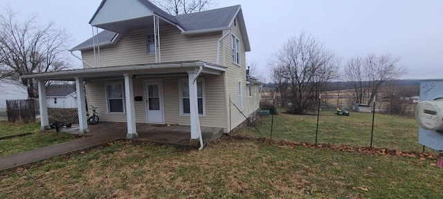 traditional-style home featuring covered porch, a front yard, and fence