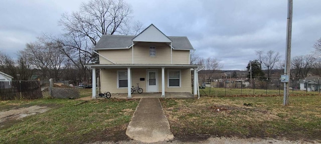 view of front of house featuring covered porch, a front lawn, and fence