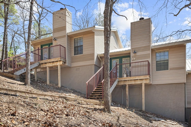 back of property with a chimney and stairs