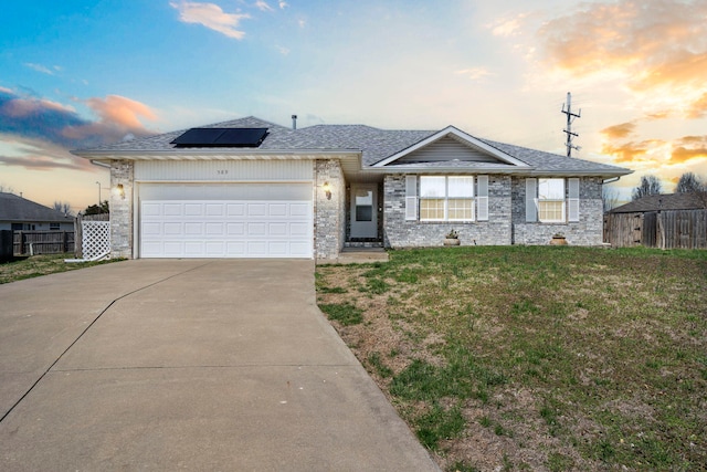ranch-style home with solar panels, fence, a garage, and driveway