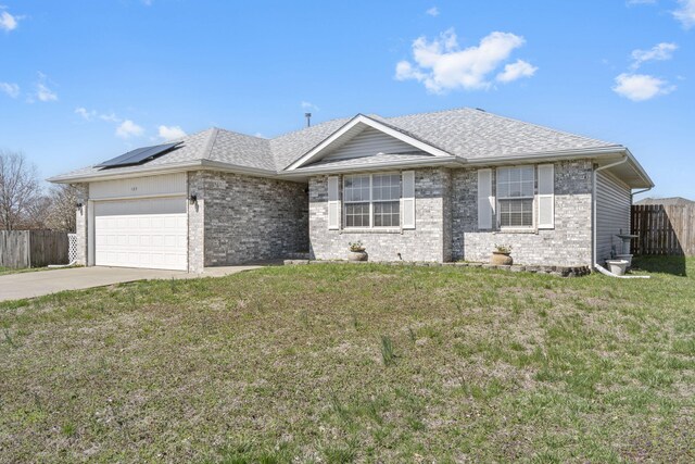 ranch-style home with fence, concrete driveway, an attached garage, brick siding, and solar panels