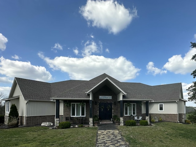 view of front of property with brick siding, a front yard, and roof with shingles