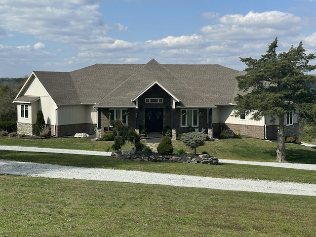 craftsman inspired home with roof with shingles, stone siding, and a front lawn