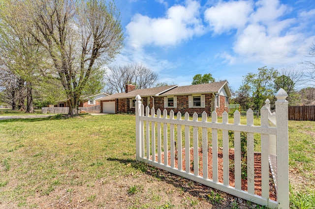 view of front of property with a fenced front yard, a chimney, an attached garage, a front yard, and brick siding