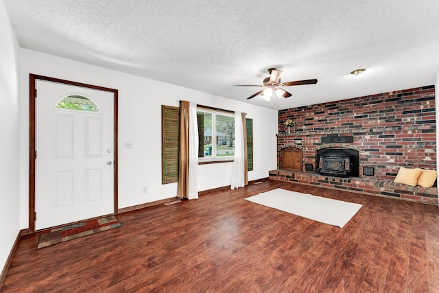 unfurnished living room with a wood stove, a healthy amount of sunlight, wood finished floors, and a textured ceiling