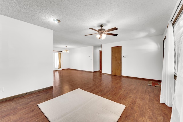 empty room with baseboards, a textured ceiling, dark wood-style floors, and ceiling fan with notable chandelier