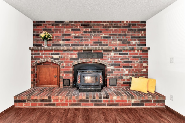 interior details featuring wood finished floors, baseboards, a textured ceiling, and a wood stove