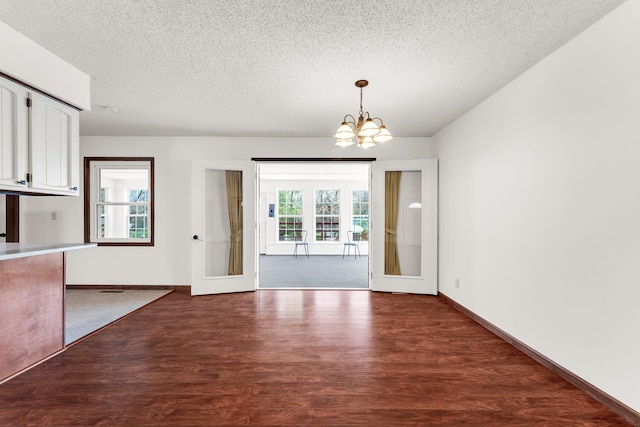 unfurnished dining area with baseboards, a chandelier, wood finished floors, and a textured ceiling