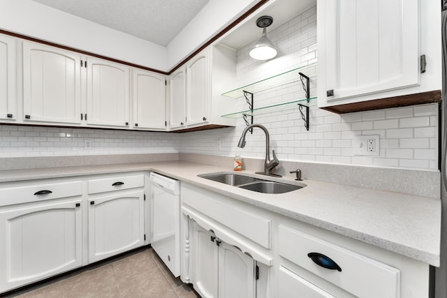 kitchen with white dishwasher, decorative backsplash, white cabinetry, and a sink