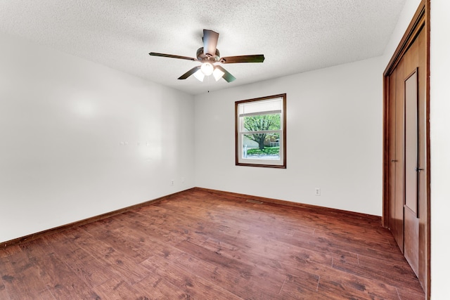 unfurnished bedroom with wood finished floors, a textured ceiling, a ceiling fan, and baseboards