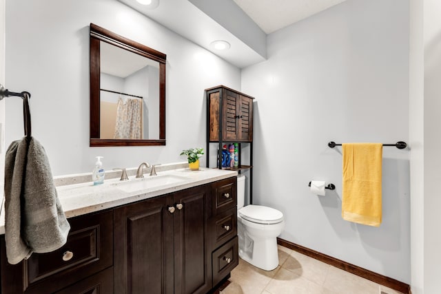 bathroom with baseboards, vanity, tile patterned flooring, and toilet