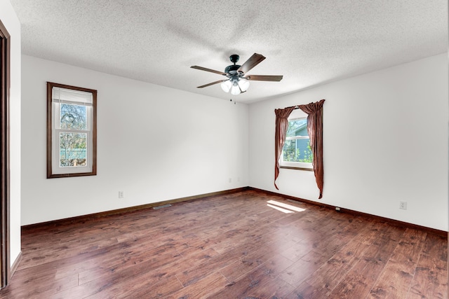 spare room featuring a wealth of natural light, dark wood-style floors, and ceiling fan