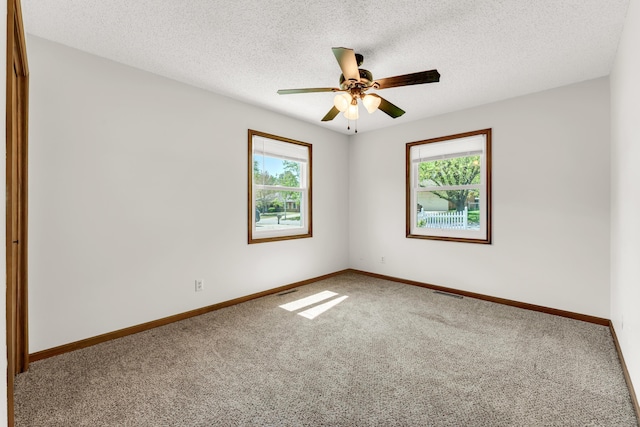 carpeted empty room with a textured ceiling, visible vents, a ceiling fan, and baseboards
